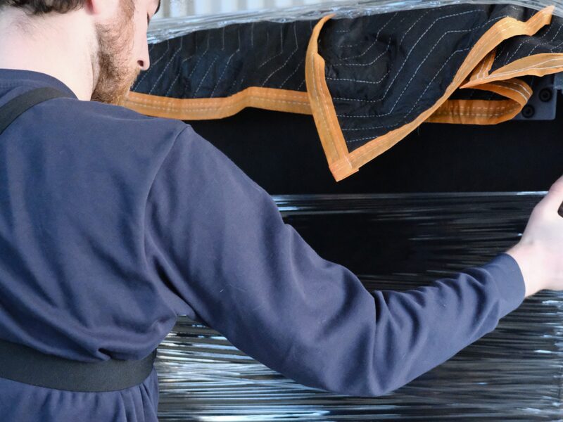 Crew member wrapping furniture in moving blankets